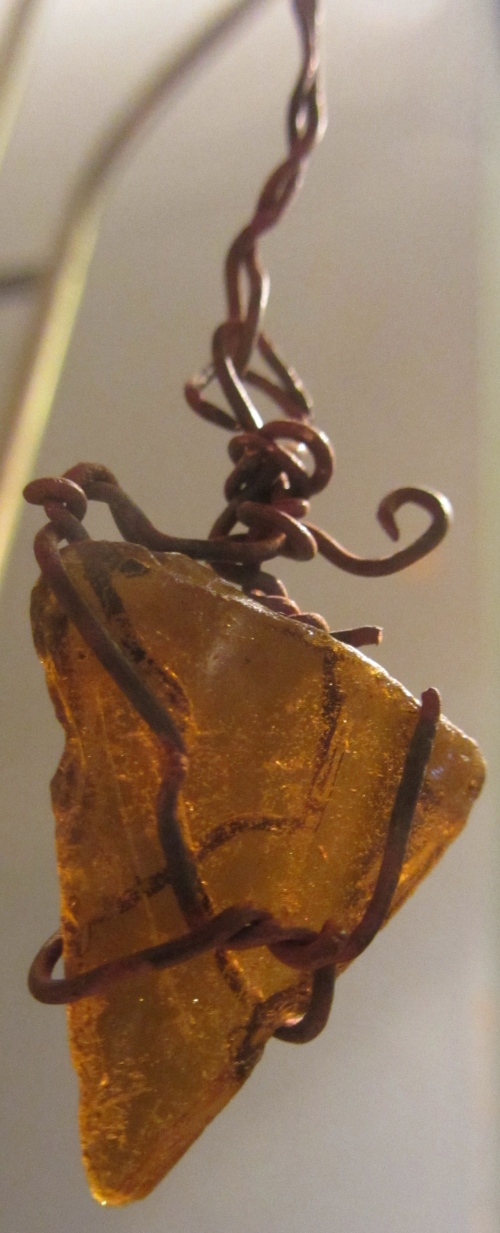 This brown glass glows amber when the light shines from behind it.  I used pliers to shape and pull the wire I found into something that would hang it from a window.